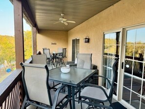An outdoor patio with a table and chairs, a ceiling fan, and a view of trees. - Lakefront 3BR condo with pool, balcony, fireplace, and resort views. (Hollister)
