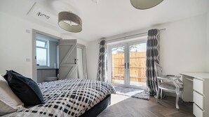 Een slaapkamer met een bed, een bureau en een stoel. Er is een raam en een deur.