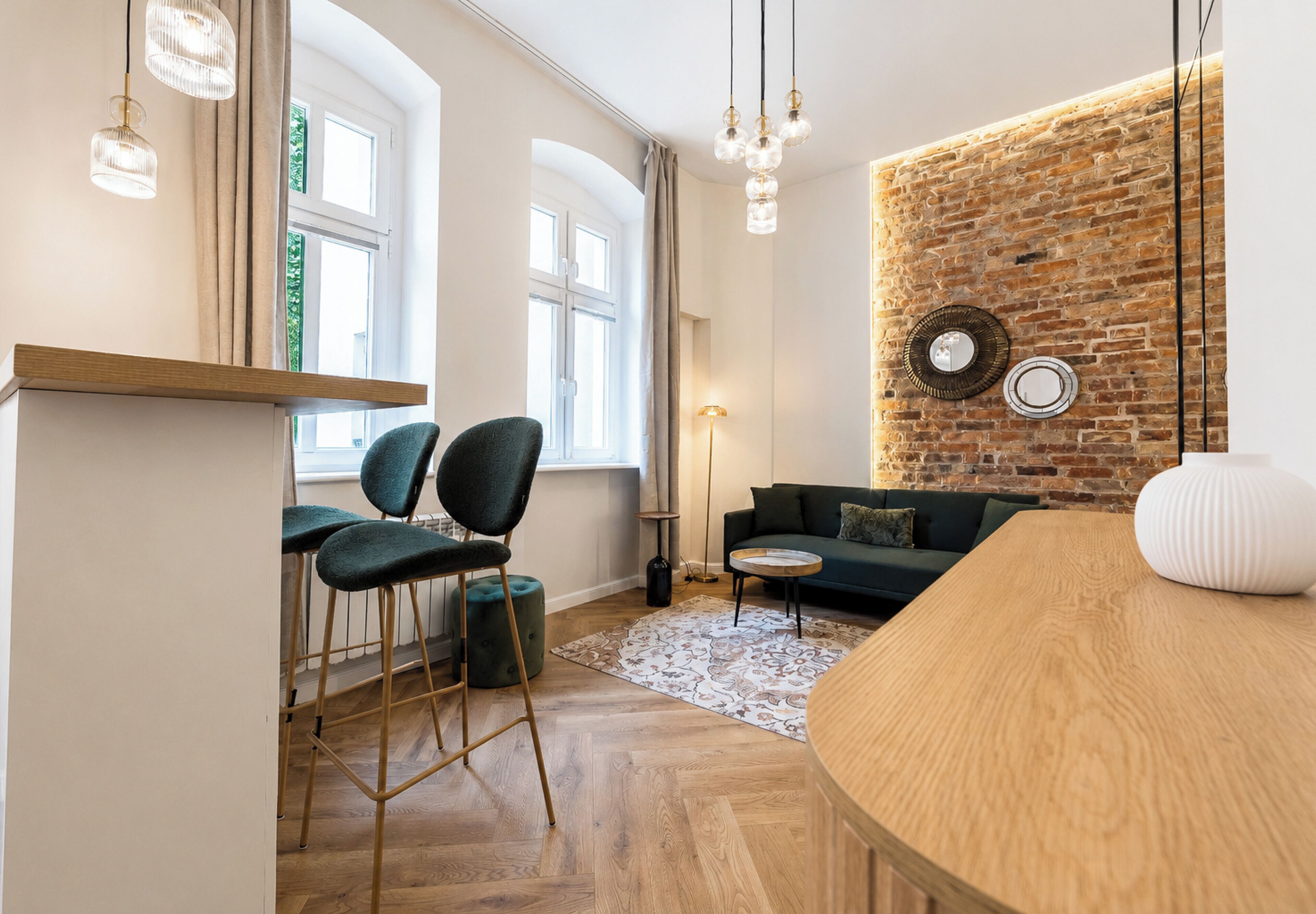Ein modernes Wohnzimmer mit Küchenbereich, einem Esstisch und einer Sitzecke inklusive Sofa und Couchtisch.