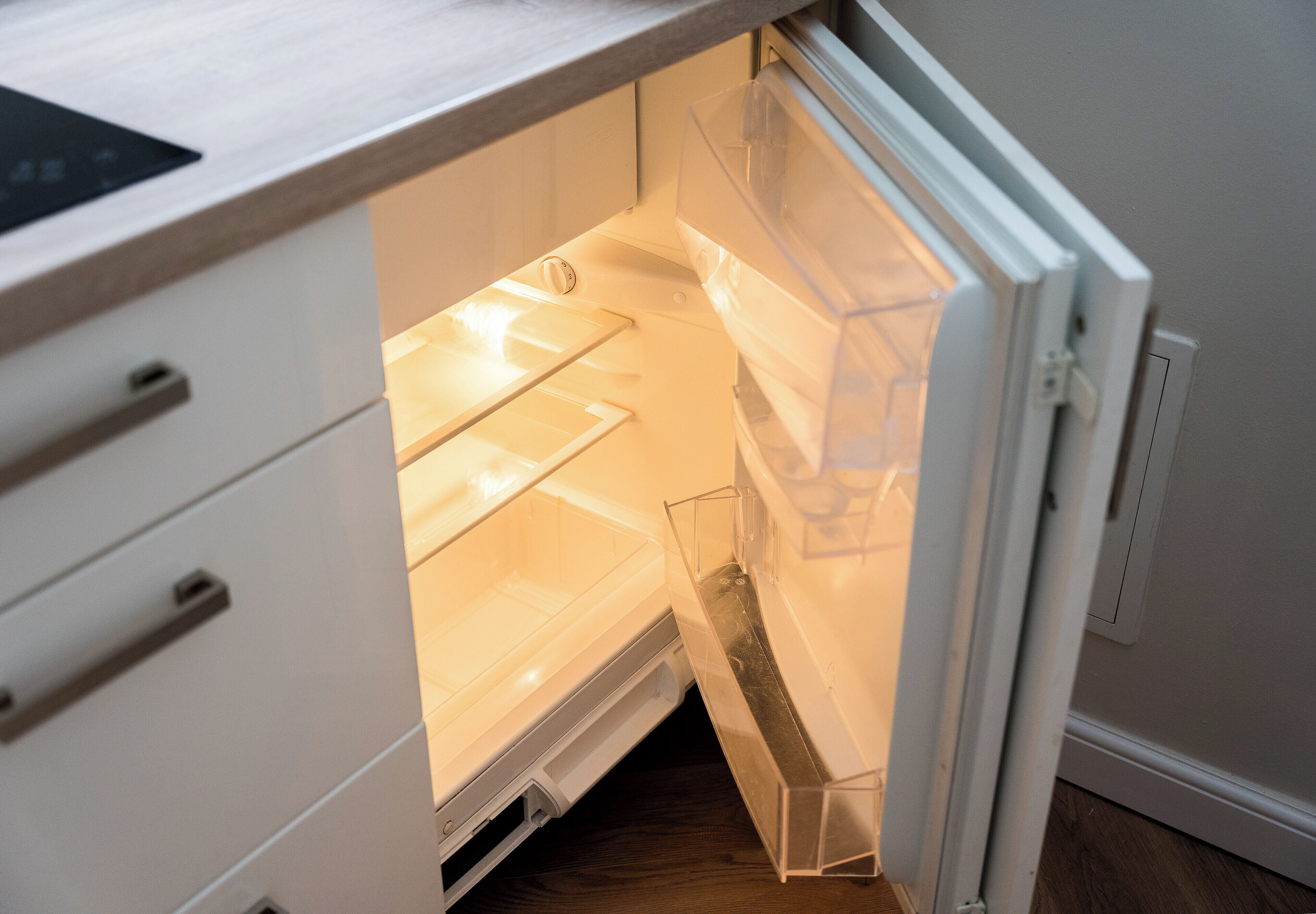 An open refrigerator with transparent shelves and a freezer compartment.