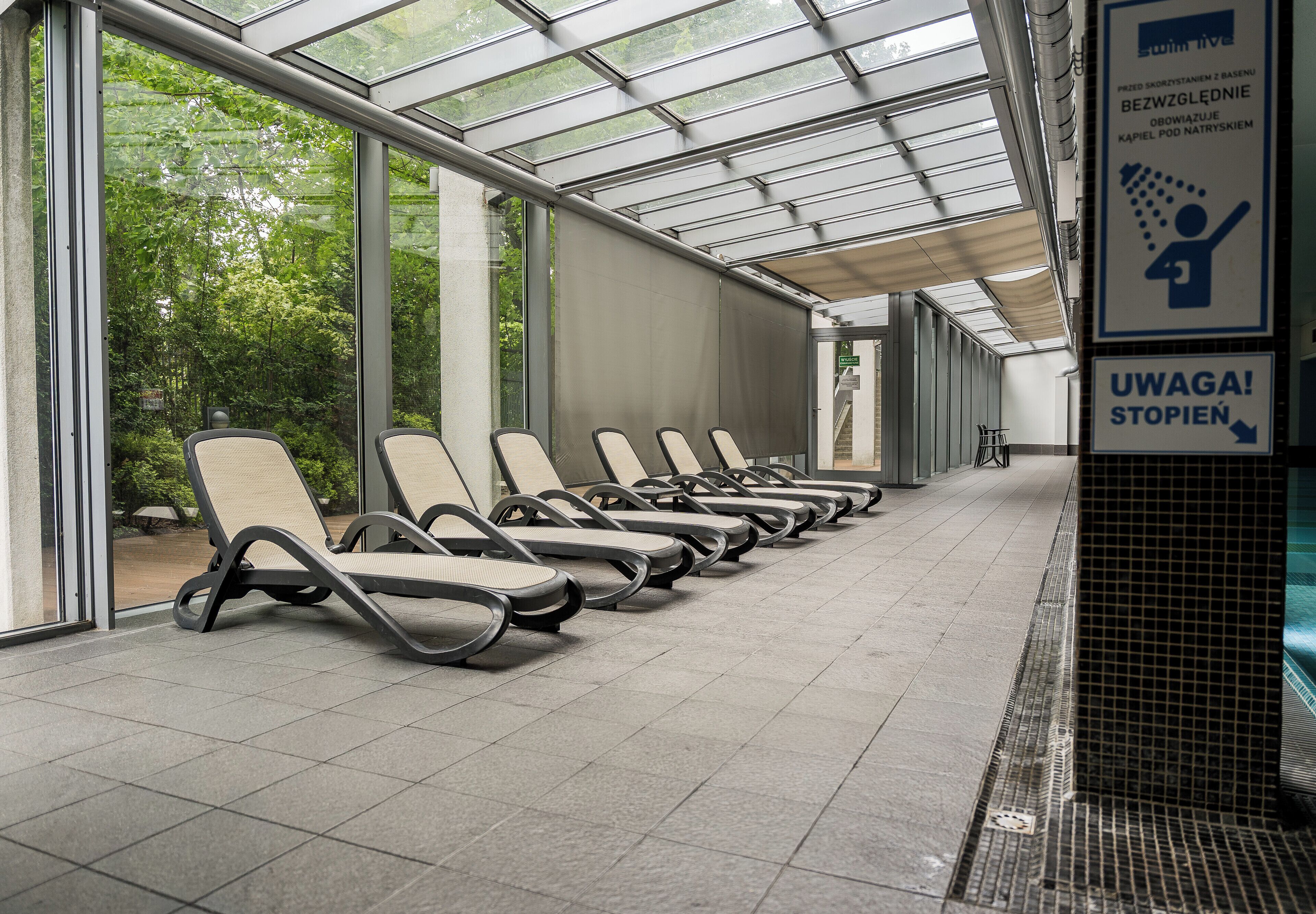 Ein überdachter Wartebereich mit Reihen von Stühlen und einer Glasdecke.