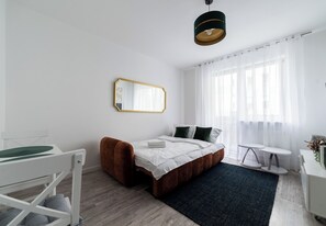 Ein modernes Schlafzimmer mit Bett, Nachttisch, Stuhl, einem kleinen runden Tisch und einem Spiegel an der Wand.