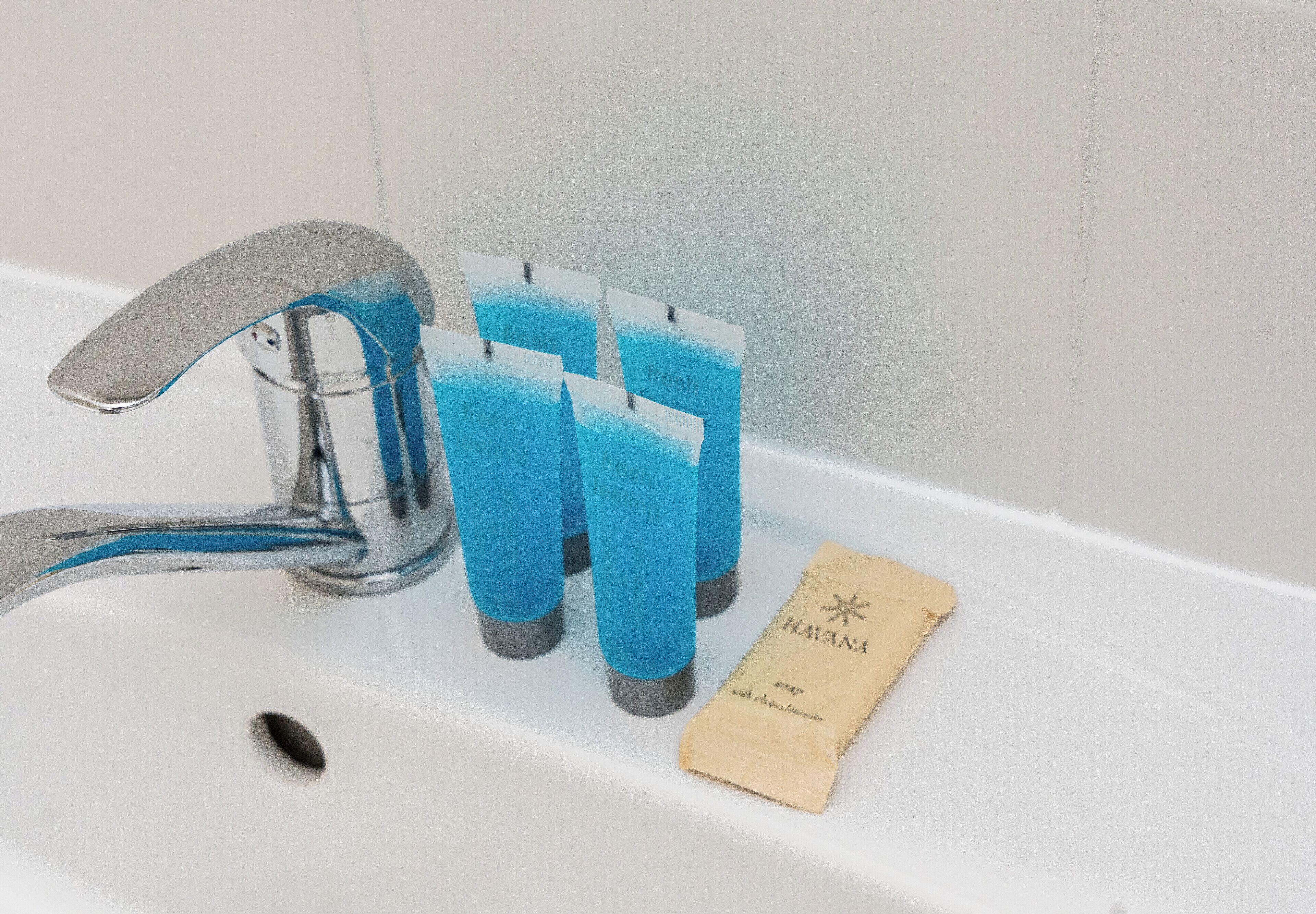 A bathroom sink with a faucet, four blue toothbrush holders, and a small brown paper bag with the word 'HAVANA' on it.