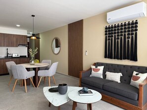 Ein modernes Wohnzimmer mit einer Couch, einem Esstisch, Stühlen und einem Couchtisch.