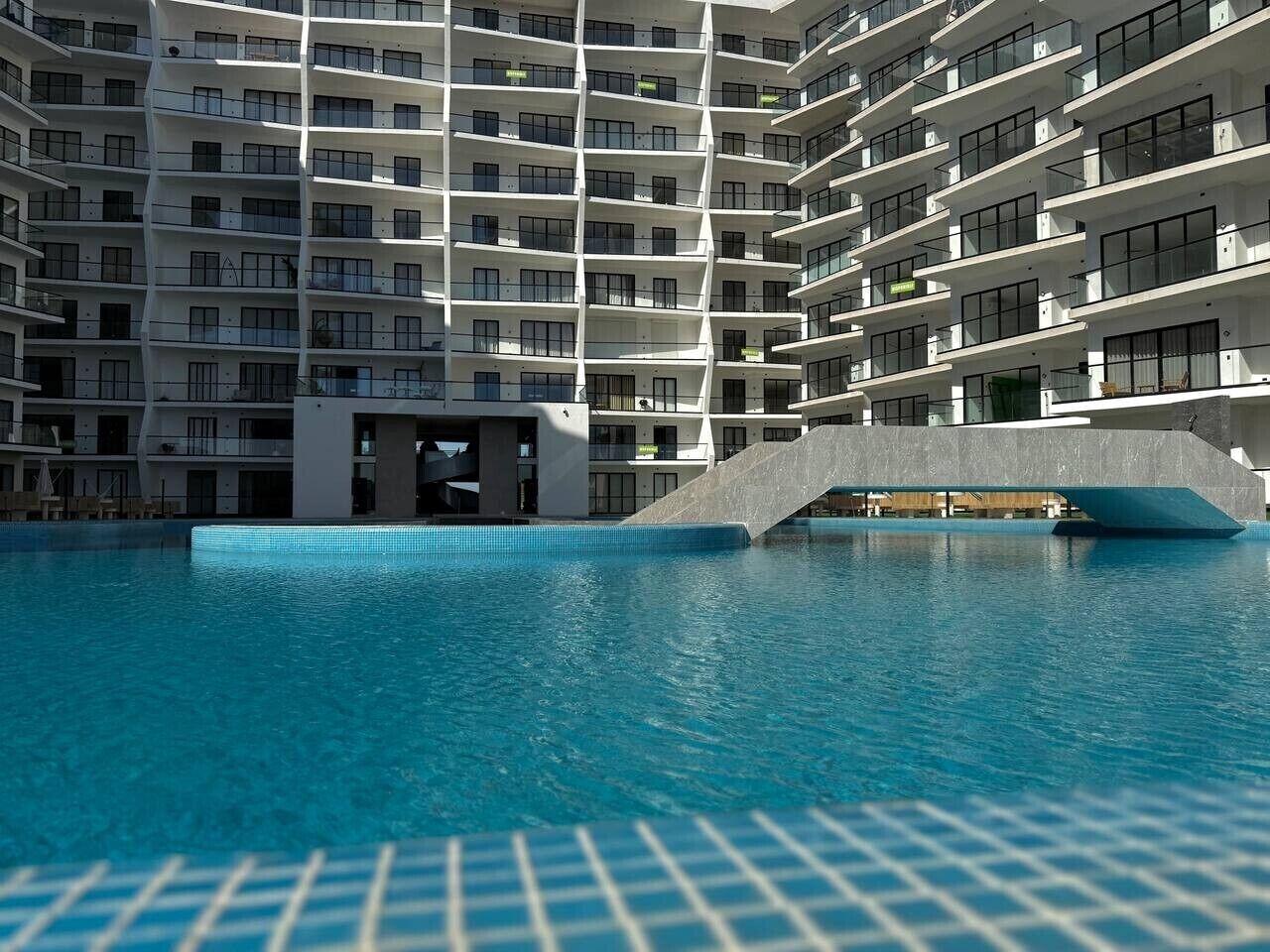 A modern building with a pool, balconies, and a unique architectural design.