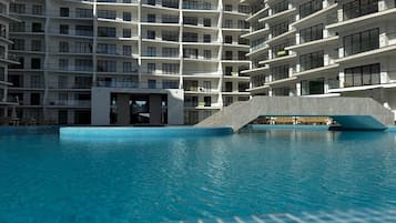 A modern building with a pool, balconies, and a unique architectural design.