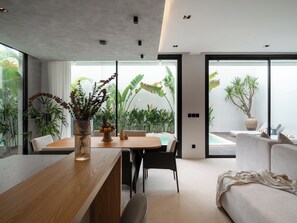 Un interior moderno con comedor, sofá y vistas al exterior.