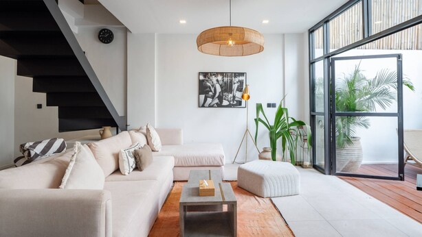 A modern living room with a staircase, a large window, and a hanging light fixture. - Tribeca Bali (Bali)