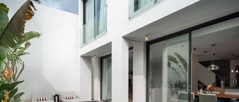 A modern house with a swimming pool, a balcony, and a dining area.