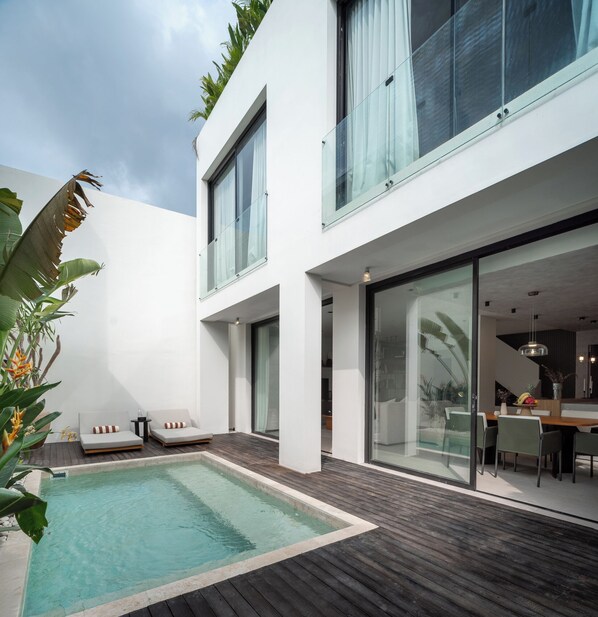 Una casa moderna con piscina, balcón y zona de comedor.