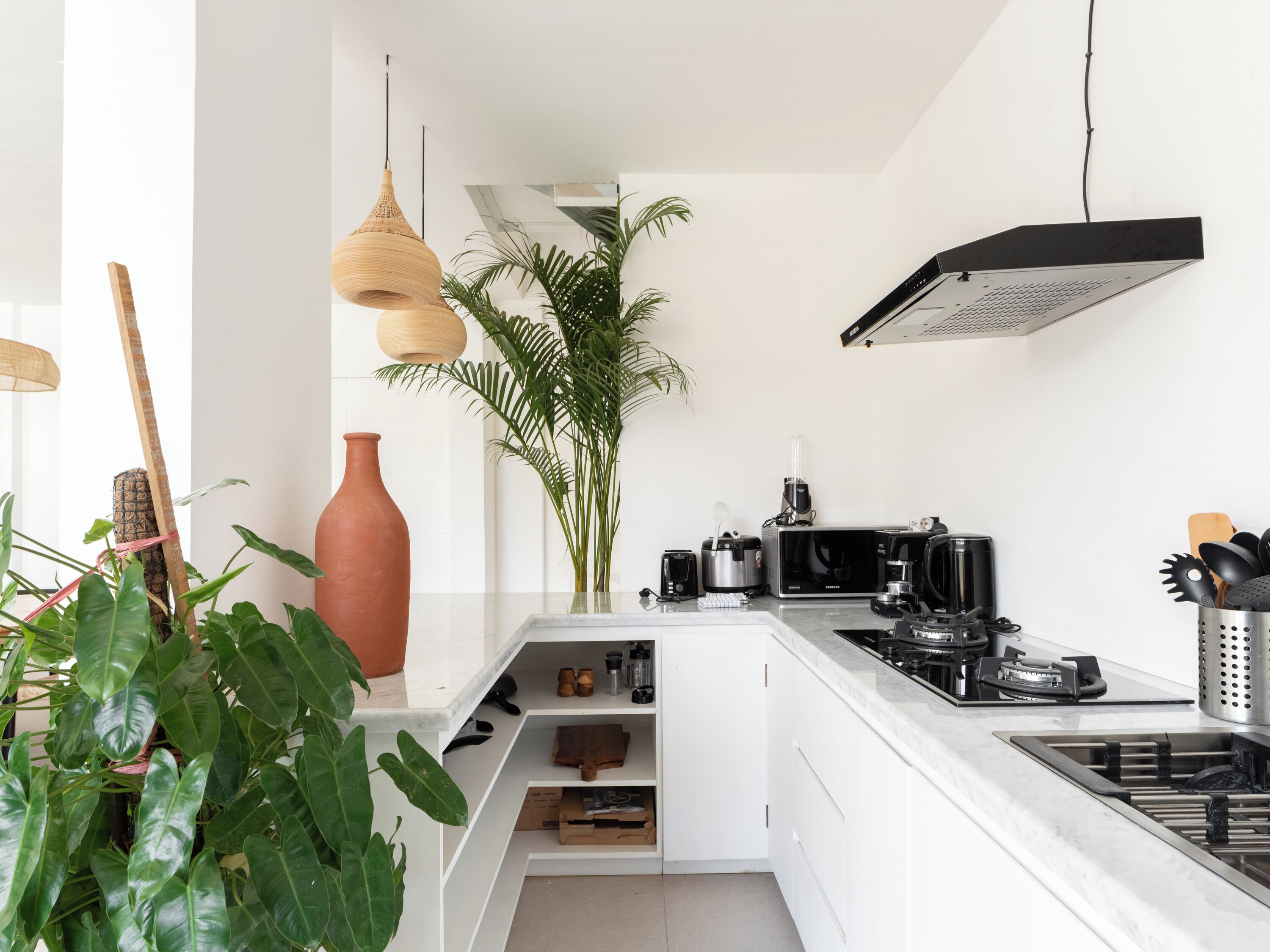 A modern kitchen with white cabinetry, a built-in stove, and various appliances.
