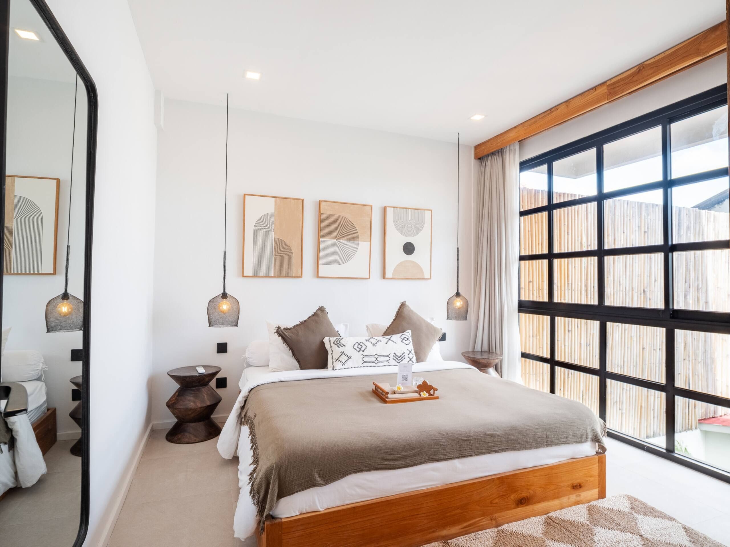 A modern bedroom with a wooden bed, a large window, and artwork on the wall.