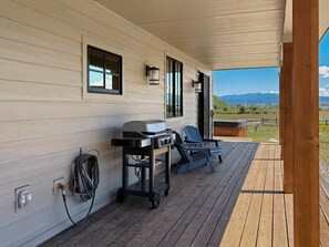 A covered outdoor area with a grill cart, a hose, and two Adirondack chairs. - LEED Gold Retreat | Hot Tub | Near Tamarack (Donnelly)