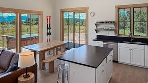 A modern kitchen with a central island, white cabinetry, and large windows offering a view of the outdoors. - LEED Gold Retreat | Hot Tub | Near Tamarack (Donnelly)
