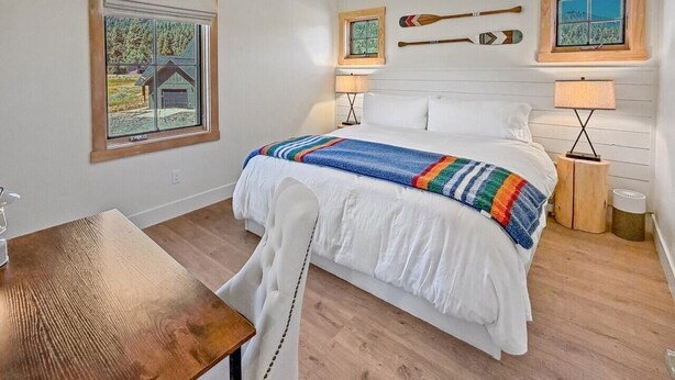 A bedroom with a bed, a window, a table, and a lamp. - LEED Gold Retreat | Hot Tub | Near Tamarack (Donnelly)