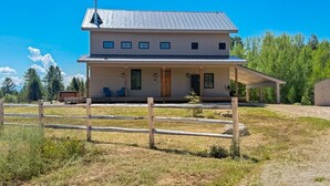 A two-story building with a covered porch and a fenced yard. - LEED Gold Retreat | Hot Tub | Near Tamarack (Donnelly)