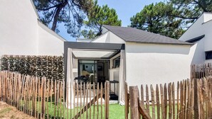 A modern house with a covered outdoor area, a wooden fence, and a well-maintained lawn. - 2 bedroom awesome home in Meschers-sur-Gironde (Meschers-sur-Gironde)