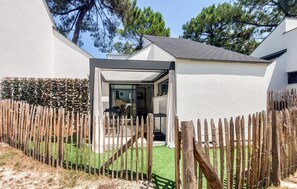 Ein modernes Haus mit überdachter Terrasse, Holzzaun und gepflegtem Rasen.