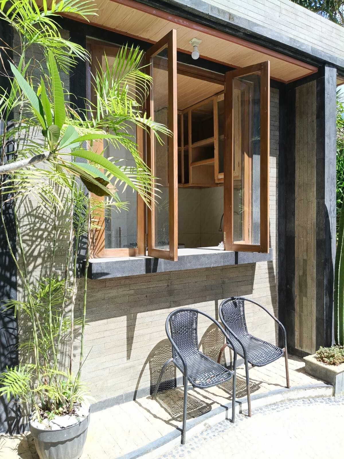 Ein modernes Gebäude mit großen Fenstern, einer Holzterrasse und Sitzgelegenheiten im Freien.