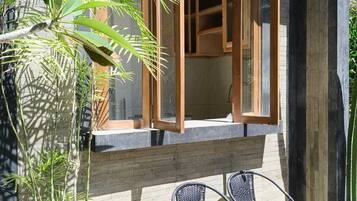 A modern building with large windows, a wooden deck, and outdoor seating.