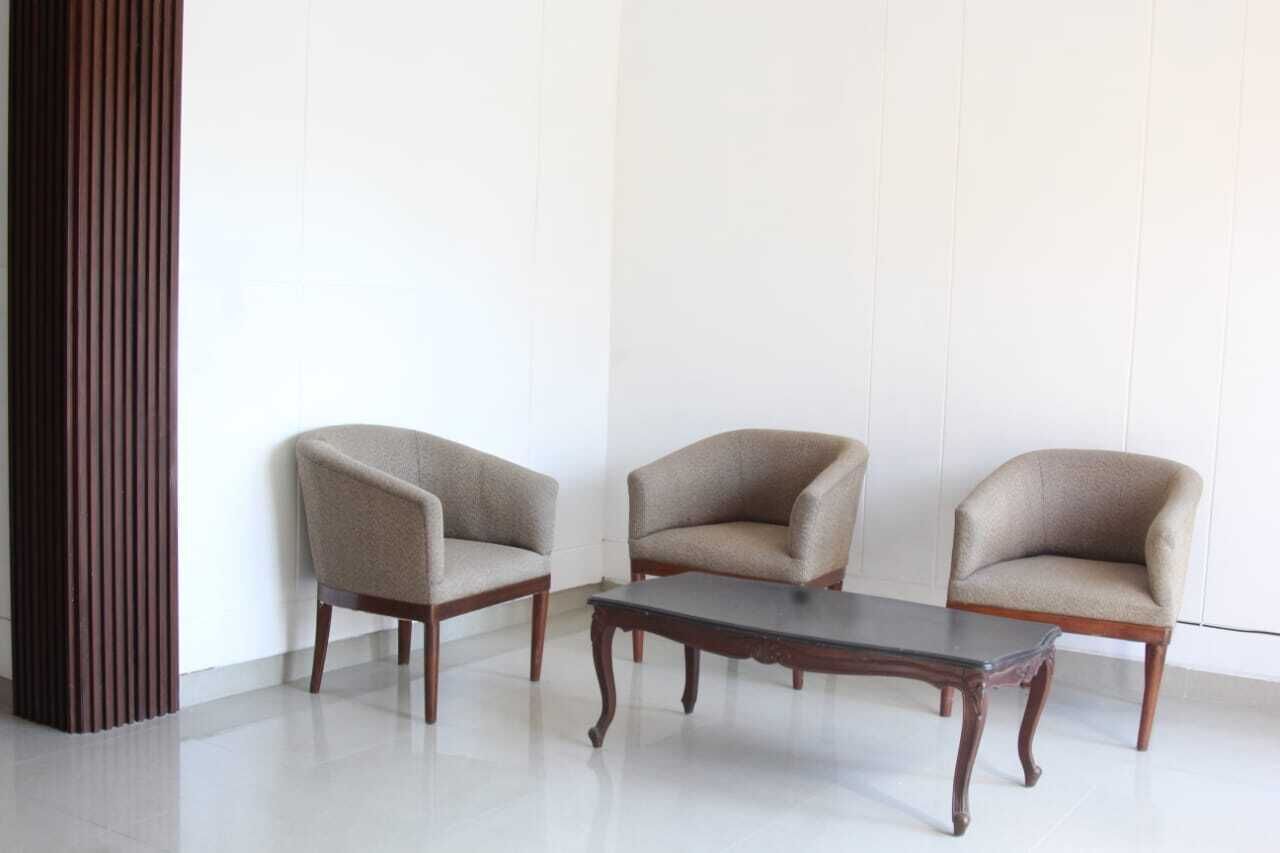 Una habitación con tres sillones y una mesa de centro de madera.
