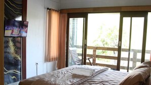 Ett hotellrum med en säng, en tv på väggen och utsikt över omgivningarna.