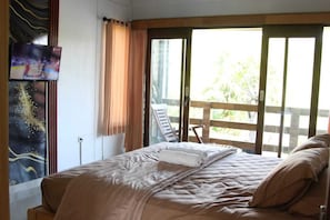 Ein Hotelzimmer mit einem Bett, einem an der Wand befestigten Fernseher und Blick ins Freie.