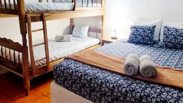 Um quarto de dormitório com beliches, um banco de madeira e chão de azulejos.