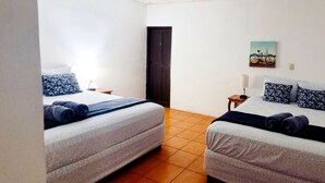 Ein Zimmer mit zwei Betten, einer Tür, einem kleinen Tisch und einem Bild an der Wand.