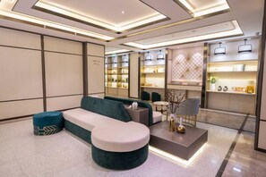 Um lobby moderno de hotel com área de estar, balcão de recepção e bar.