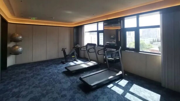 A room with exercise equipment, large windows, and a patterned carpet. - Crystal Hotel Zhongguancun Renmin Univ. (Beijing)
