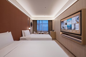 Ein Hotelzimmer mit zwei Betten, einem Fernseher und Blick auf die Stadt.