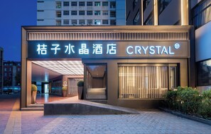 Ein Hotel mit modernem Design, dessen Eingang durch eine auffällige, beleuchtete Beschilderung und eine Glasfassade gekennzeichnet ist.