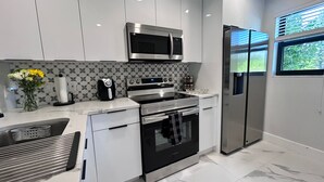 Et moderne køkken med rustfrie apparater, et mønstret backsplash og et vindue med udsigt.