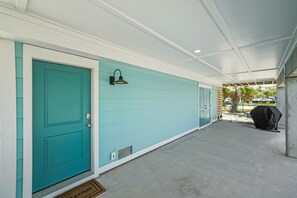 A covered porch with teal doors and a wall-mounted light fixture. - Double D's by the Sea | New 2BR Coastal Retreat (Mexico Beach)