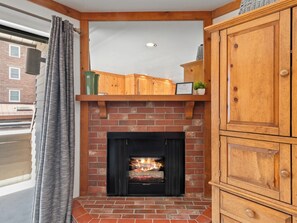 Ein Kamin mit Ziegelverkleidung, Holzregalen darüber und einem Schrank zur Rechten.