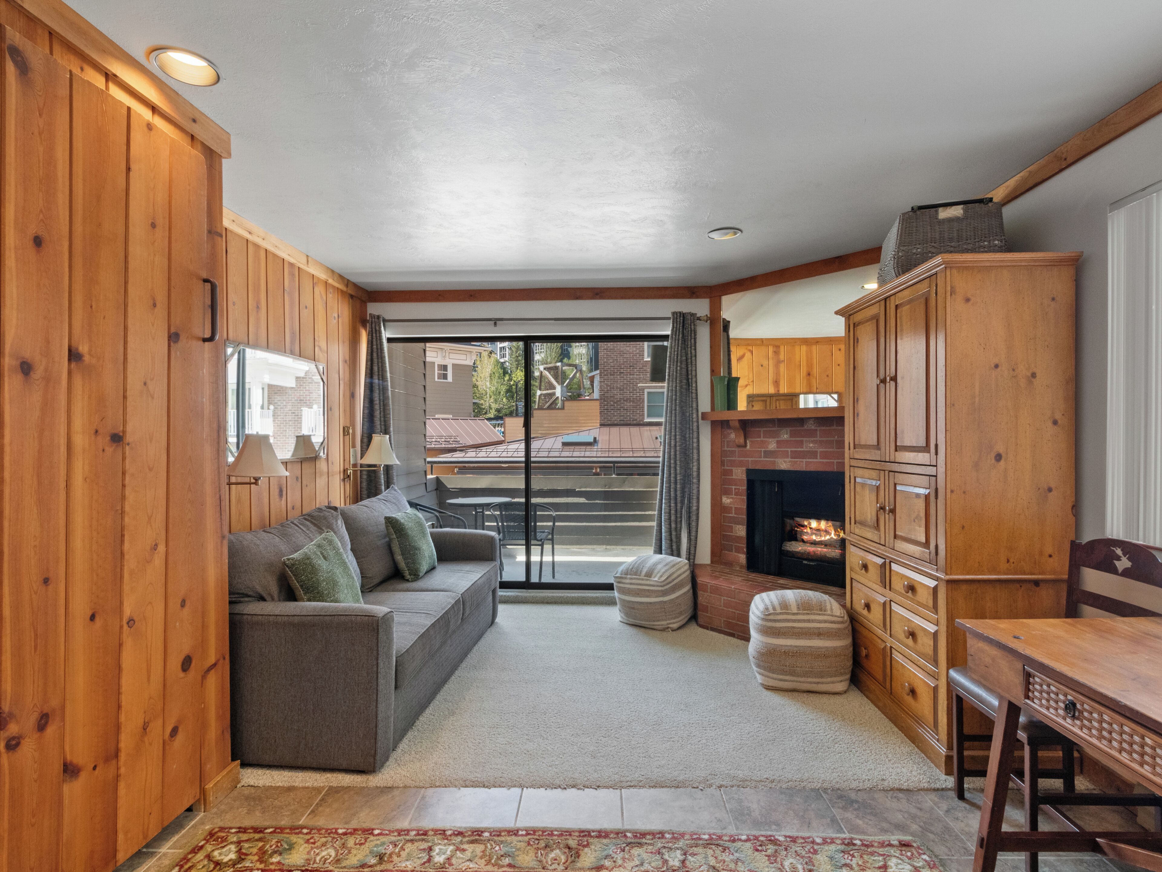A cozy living area with a sofa, ottoman, and wooden cabinets.