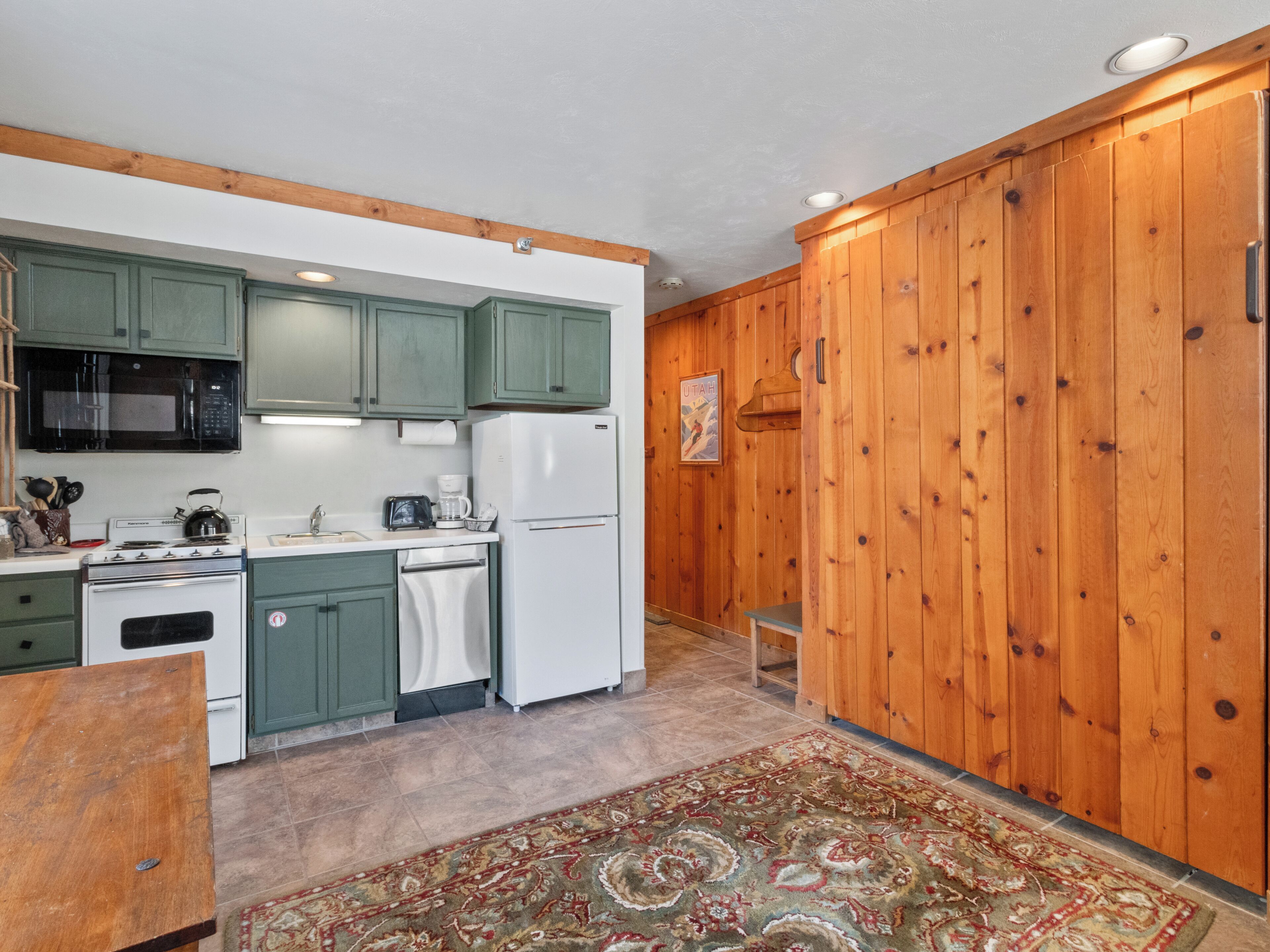 Una cocina con armarios de madera, microondas, estufa y refrigerador.