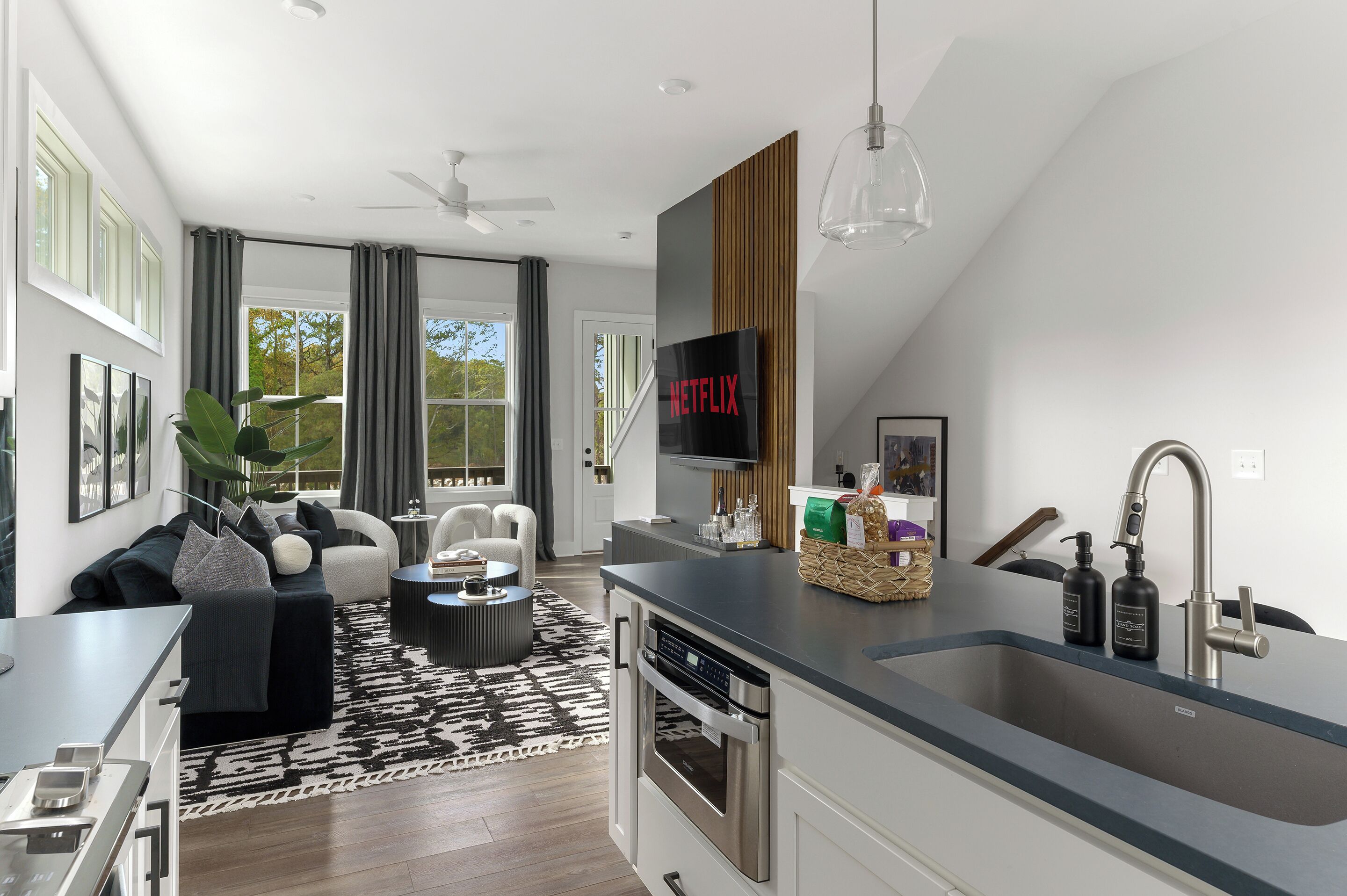 A modern kitchen with a built-in oven, a sink with a modern faucet, and a dining area with a black and white patterned rug.