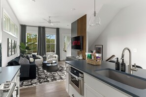 A modern kitchen with a built-in oven, a sink with a modern faucet, and a dining area with a black and white patterned rug. - Modern Luxury BeltLine Townhome Minutes to Airport, Downtown & Top Attractions. (Atlanta)