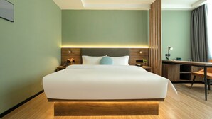 Quarto de hotel com uma cama grande, mesas de cabeceira, uma escrivaninha e uma cadeira.