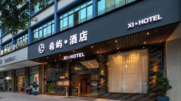 A hotel with a modern facade, large windows, and a prominent signage for 'XI HOTEL'.