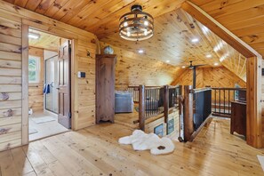 A wooden interior with a high ceiling, a staircase, and a large window. - Secluded 3 Bedroom Cabin on 100 Acres (Canandaigua)