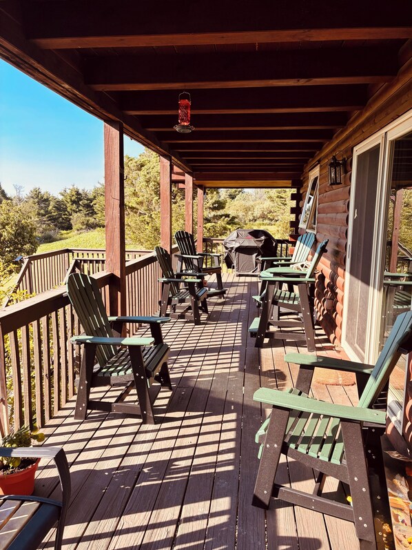 A wooden deck with outdoor seating and a barbecue grill.