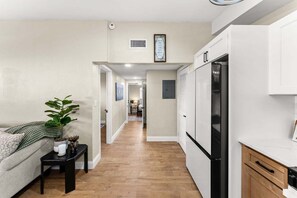 Eine moderne Küche mit weißen Schränken, einem schwarzen Kühlschrank und einem Essbereich mit Tisch und Stühlen.
