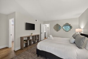 A bedroom with a bed, a TV, a console table, and a door.