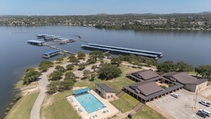 An aerial view of a lakeside property with a swimming pool, parking area, and multiple buildings.