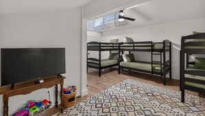 A room with bunk beds, a television on a wooden stand, and a patterned rug.