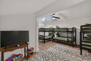 A room with bunk beds, a television on a wooden stand, and a patterned rug.