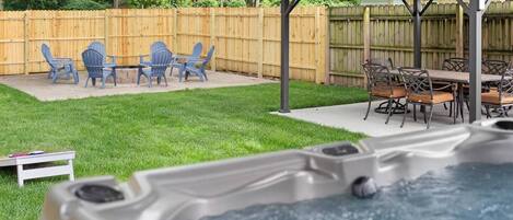 A backyard with a hot tub, a wooden deck, and outdoor furniture.